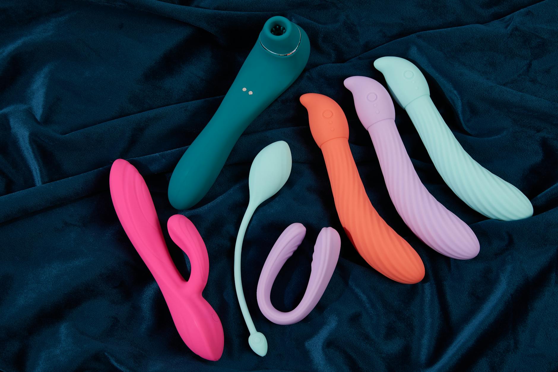 Vibratore teal su tessuto bianco e setoso, simbolo di intimità consapevole e ritorno al piacere personale