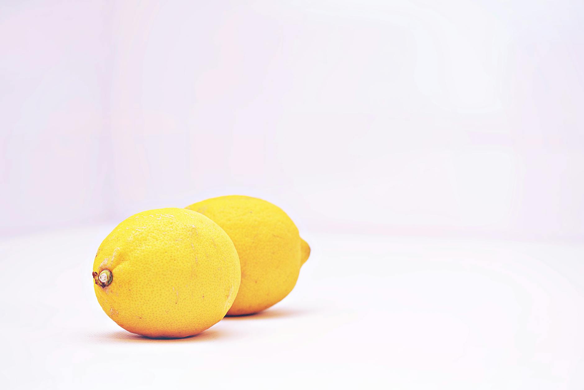Due limoni vivaci su sfondo bianco minimalista, che rappresentano il risveglio e la guarigione