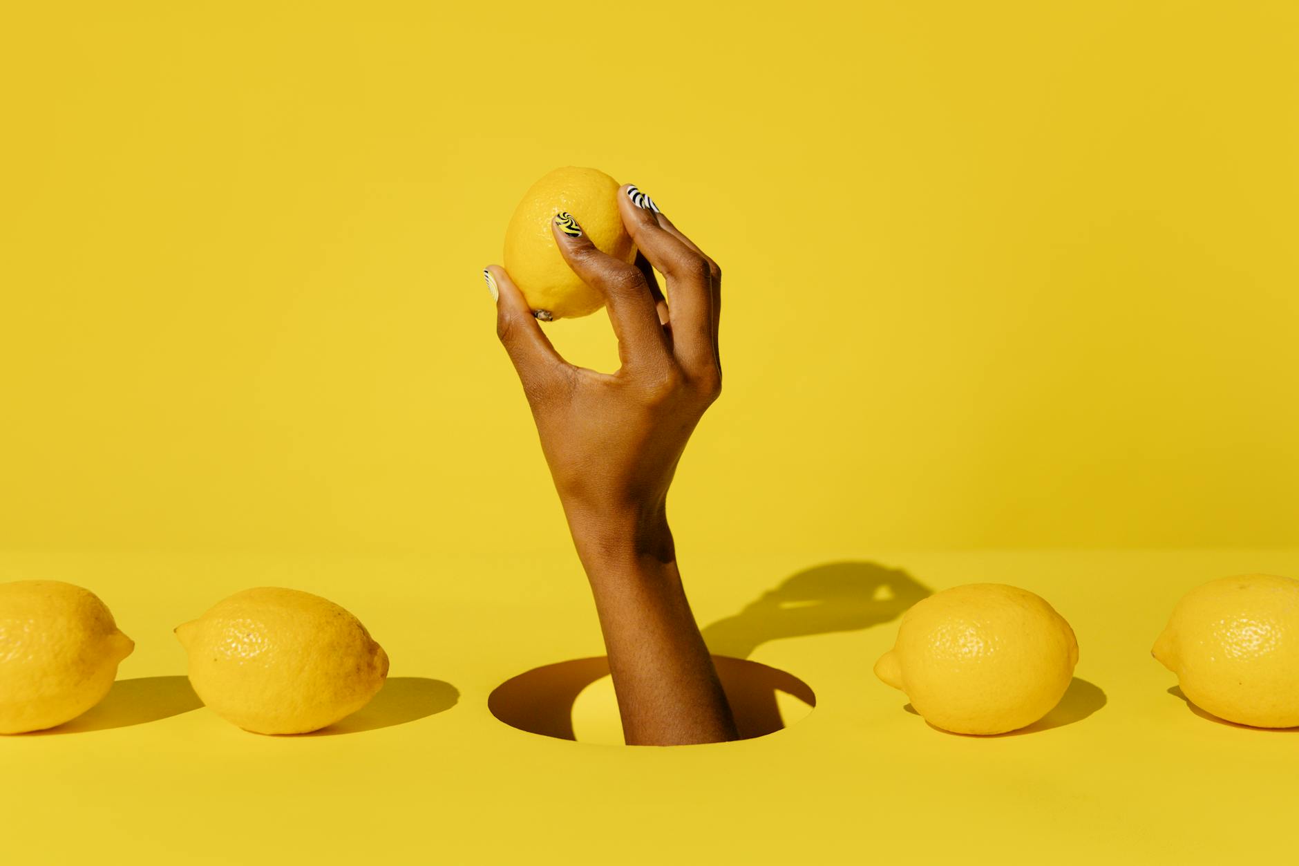 Una mano che regge un limone fresco su sfondo giallo vivace, che rappresenta la freschezza e la vitalità