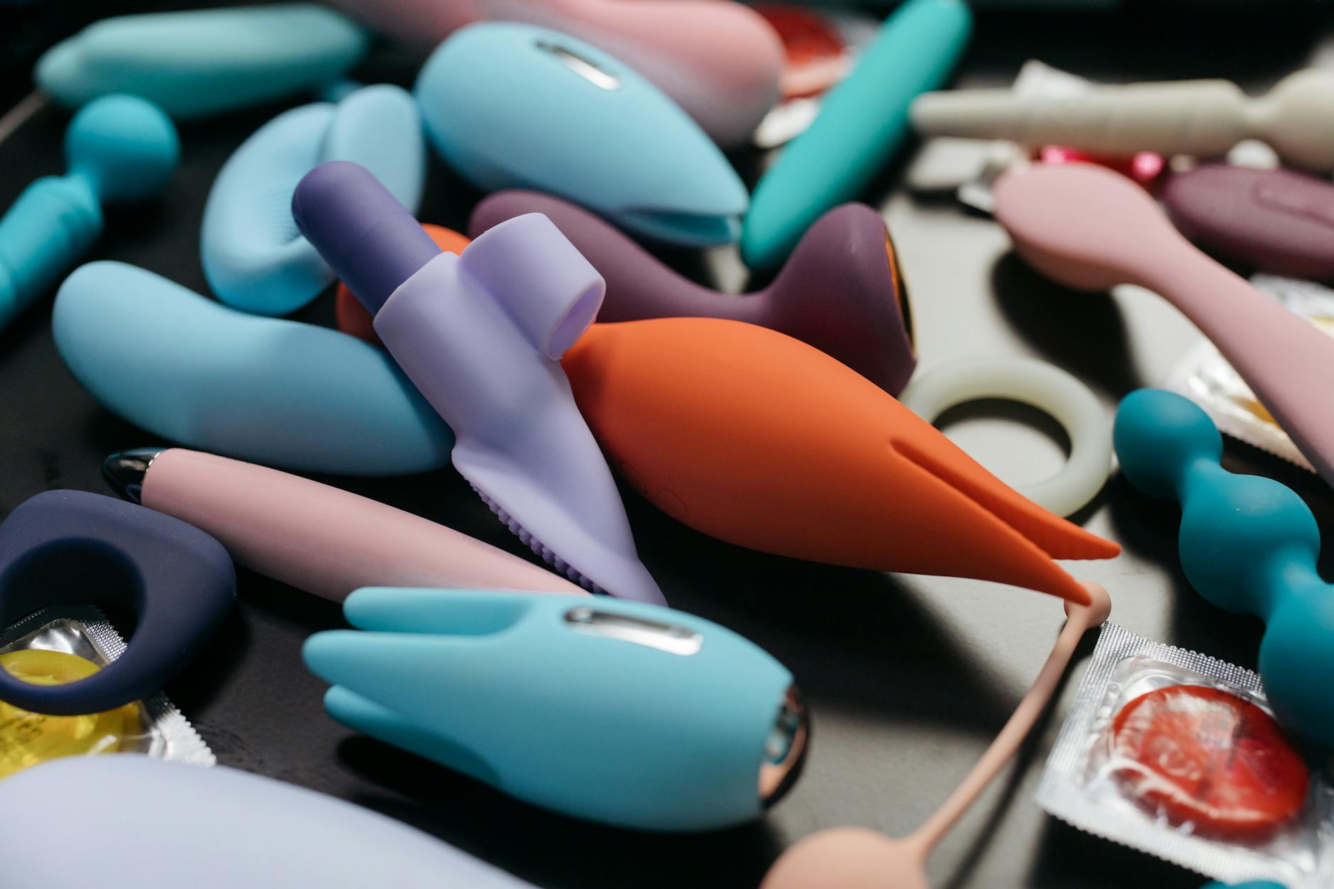 Mani che tengono un vibratore blu elegante su sfondo viola, simboleggiante l'intimità dopo i 50 anni