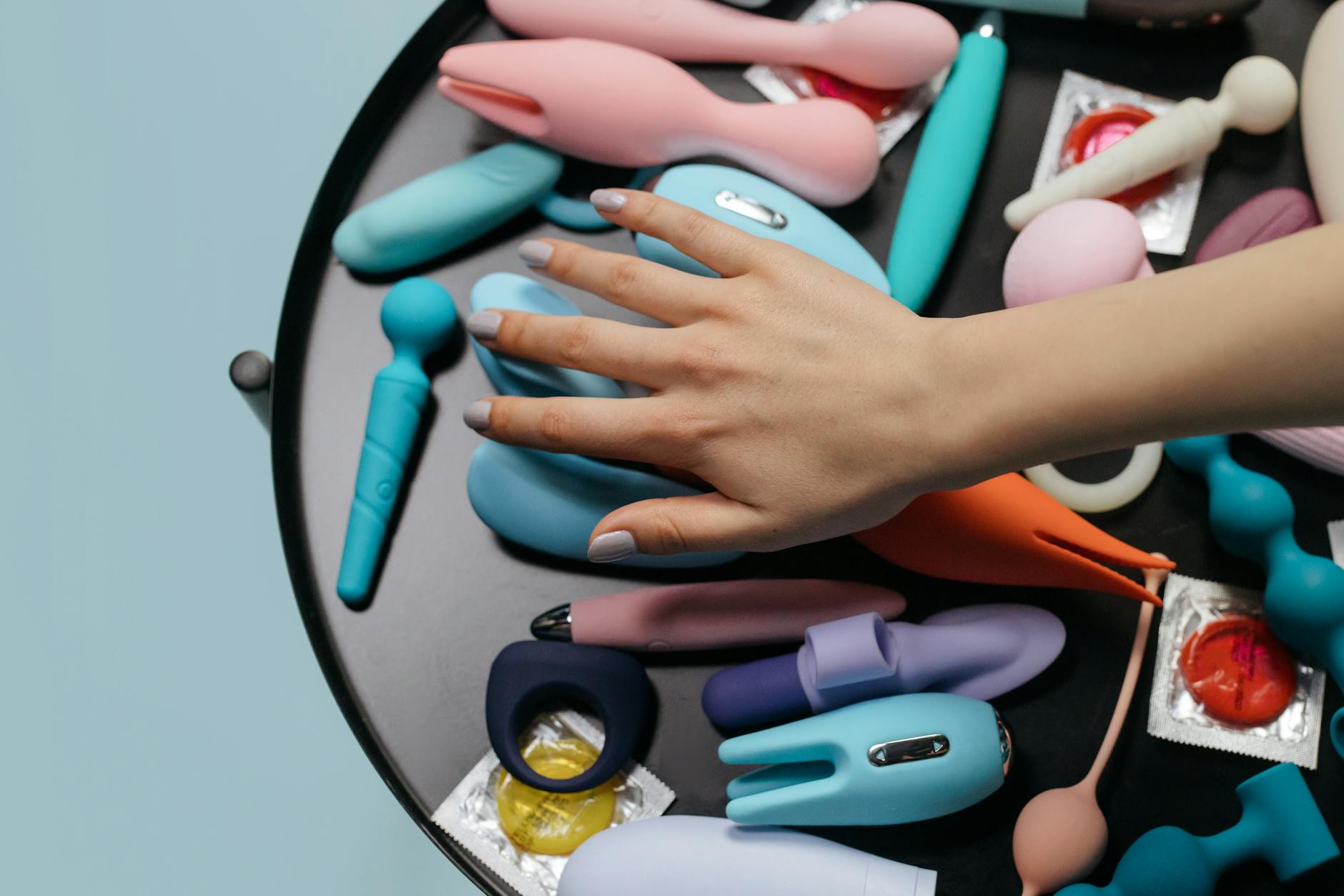 Una mano tiene un vibratore arancione minimalista su sfondo viola che mostra la sensualità moderna
