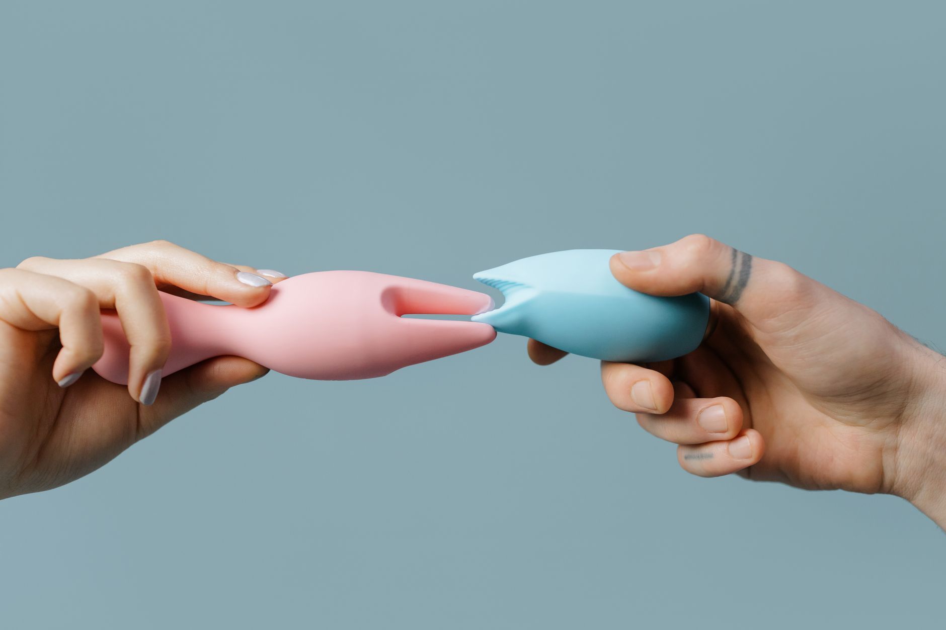 Una mano che tiene un limone su sfondo rosa morbido, circondata da altri limoni