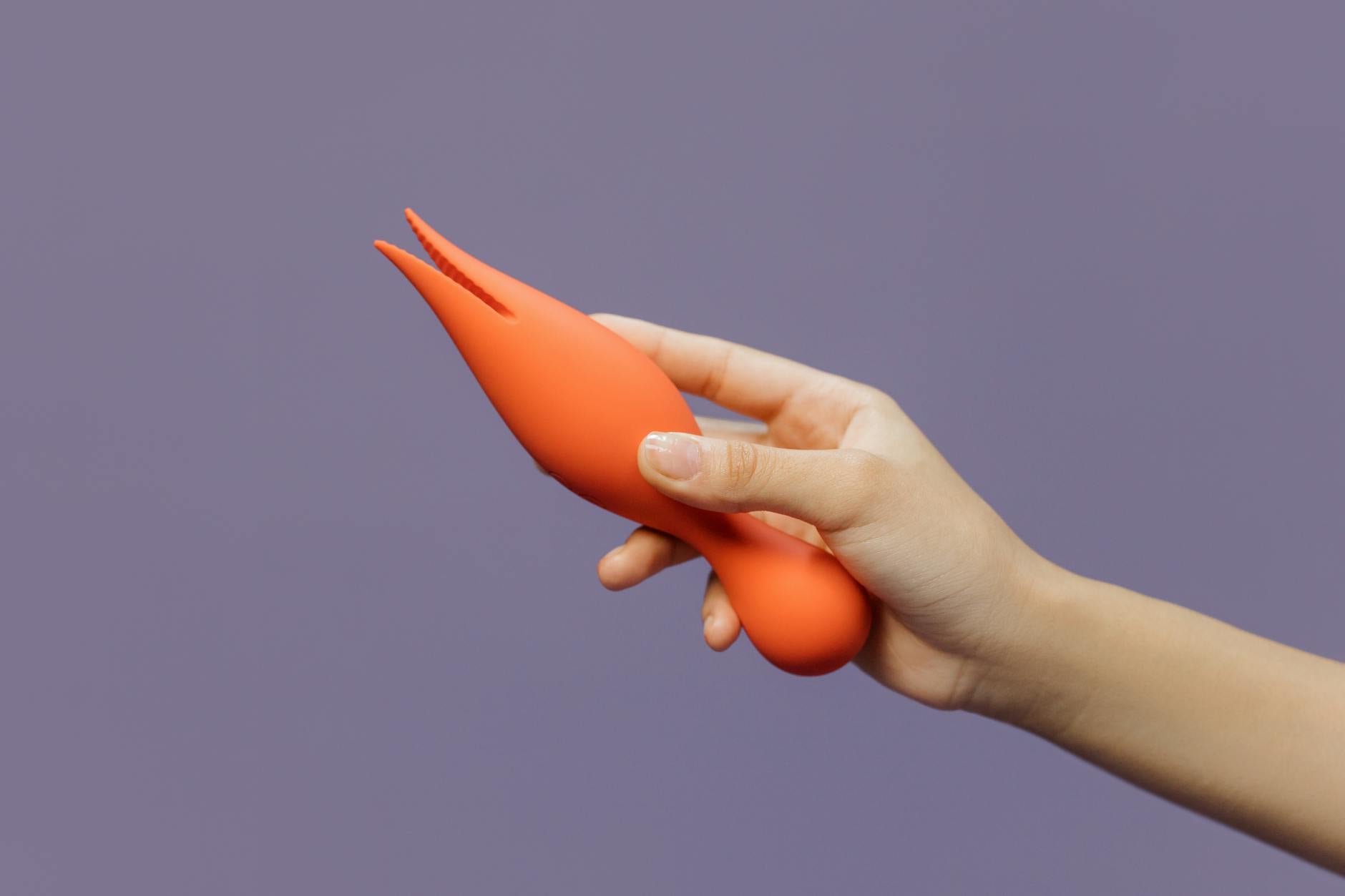 Una mano che tiene un vibratore clitorideo contro uno sfondo minimalista, mostrando sensualità moderna.