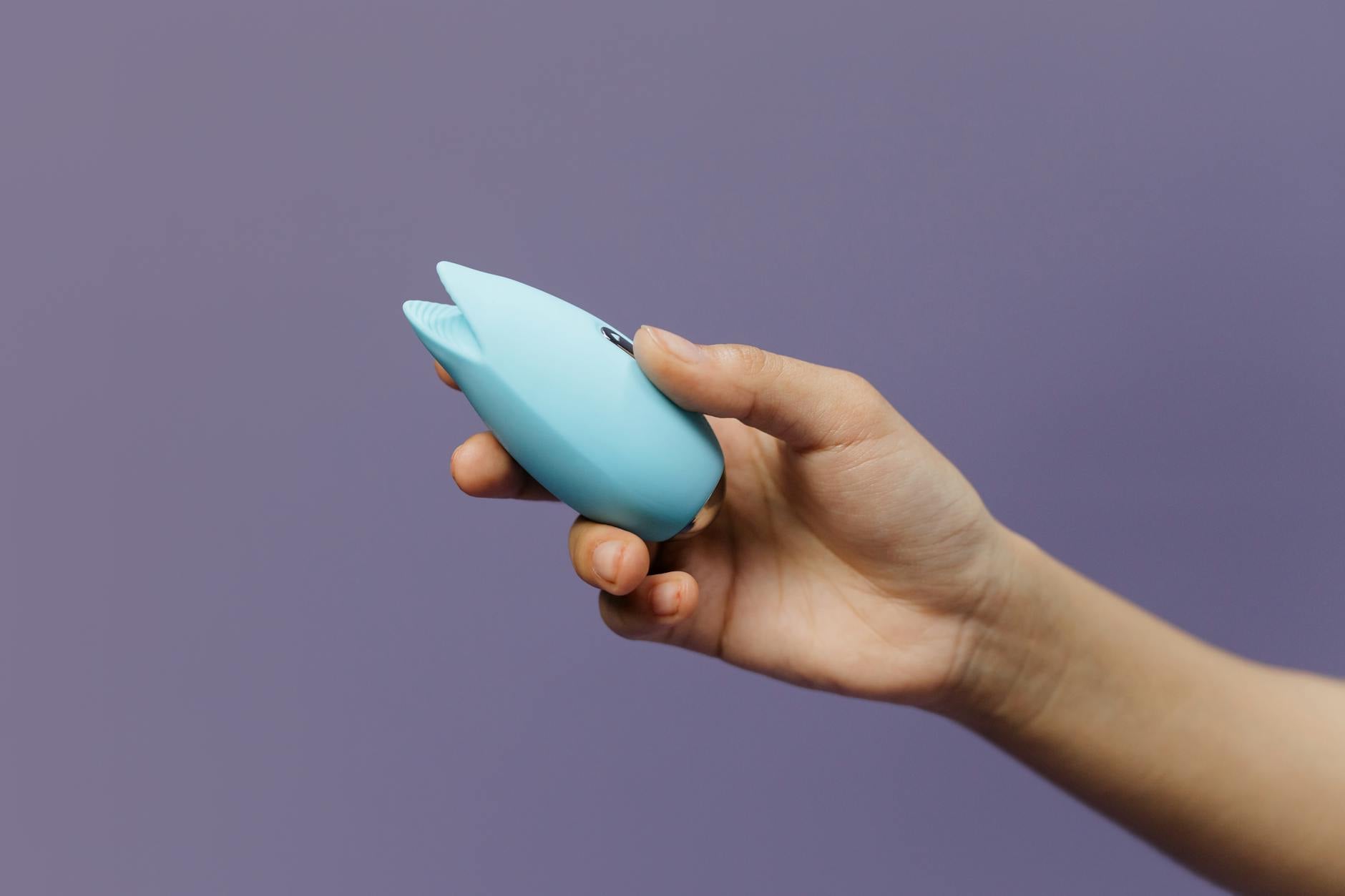 Un vibratore limone blu tenuto in mano su sfondo viola, celebrando l'amore per se stessi e la sessualità.