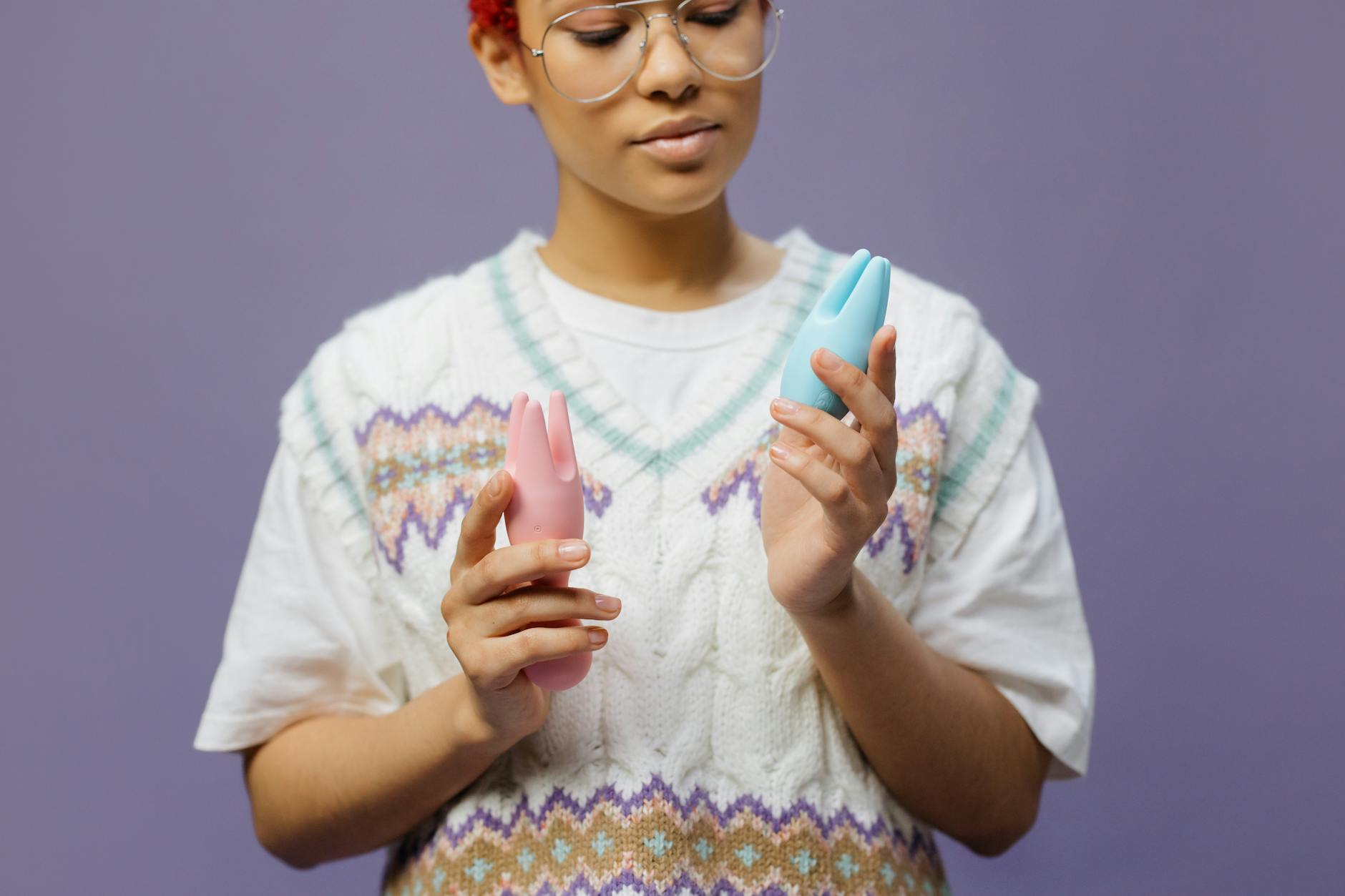 Donna che tiene vibratori sessuali colorati in mano con espressione consapevole