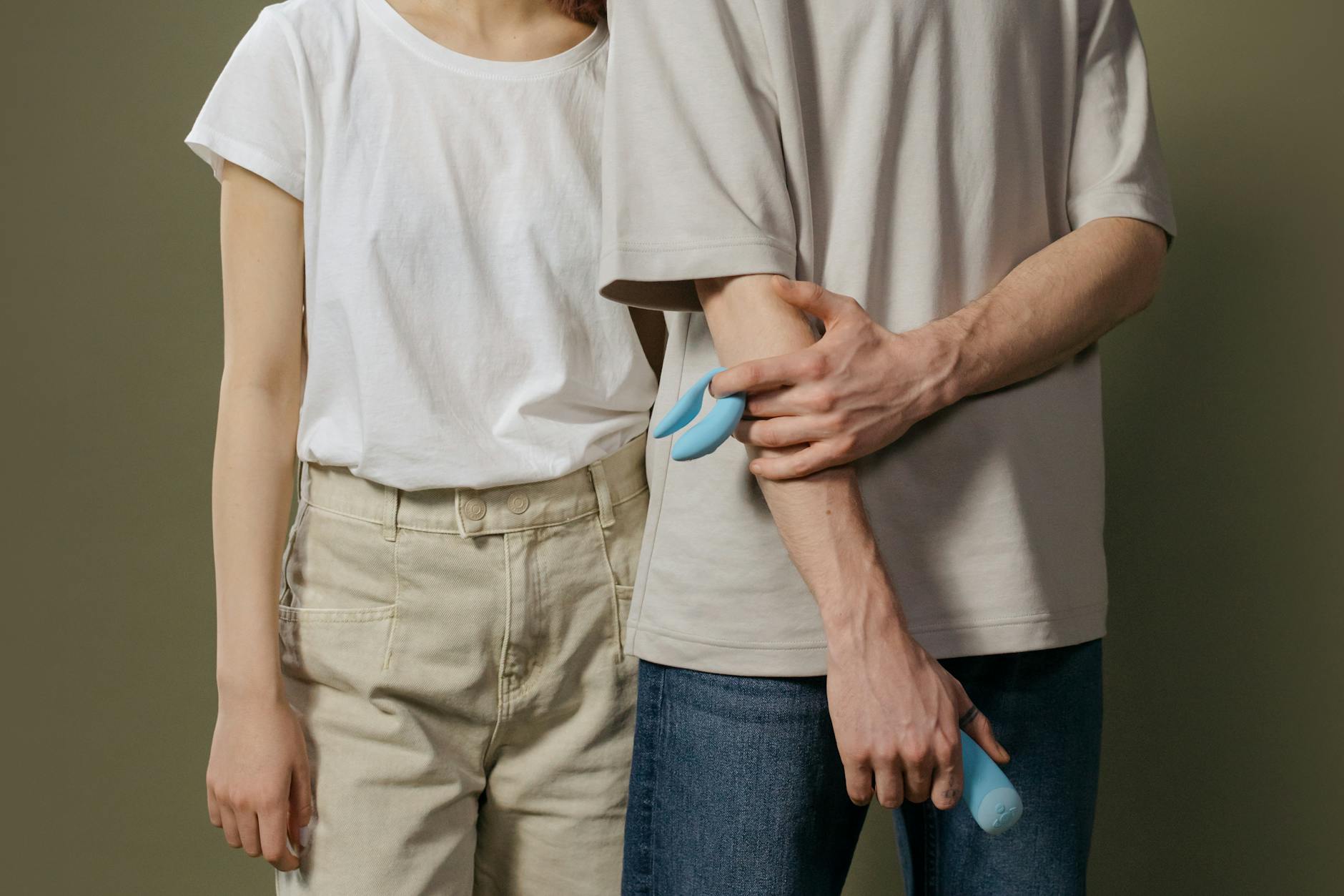 Una coppia giovane insieme al chiuso, che tiene in mano un vibratore blu, simboleggiando l'intimità moderna.