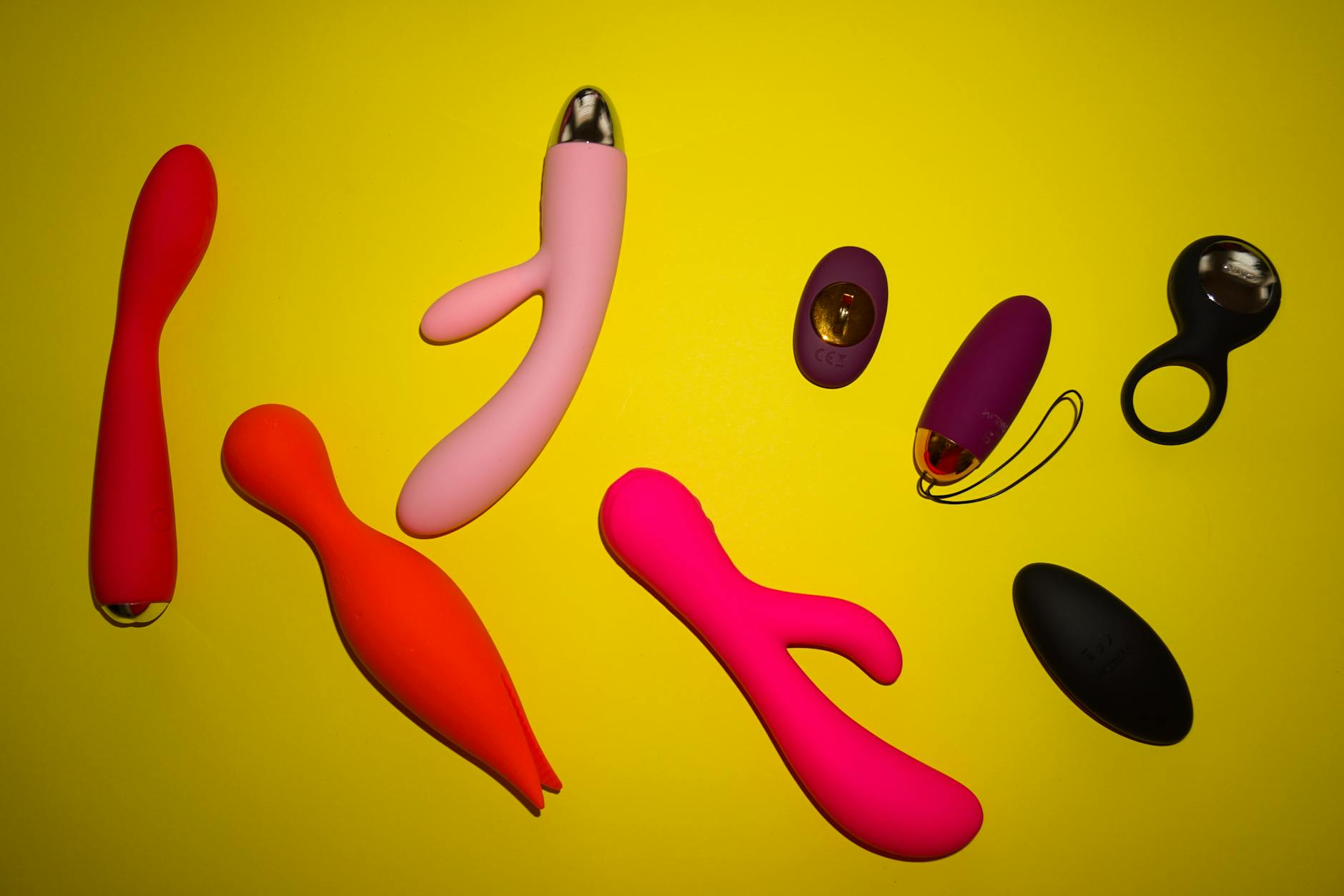 Una donna con occhiali tiene in mano vibratori in silicone blu e rosa in atteggiamento riflessivo